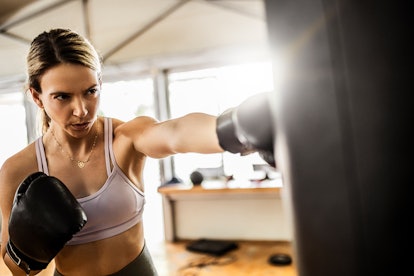 Athletic tired woman boxing in a gym, getting ready to post a funny Instagram caption