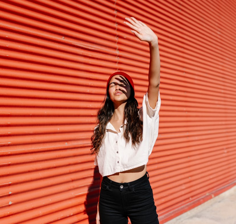 Young woman blocks sun from her face as she reflects on the spiritual meaning of the August 2022 ful...