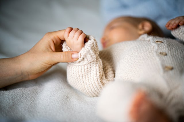 Close-up of mother's hand holding newborn baby's hand