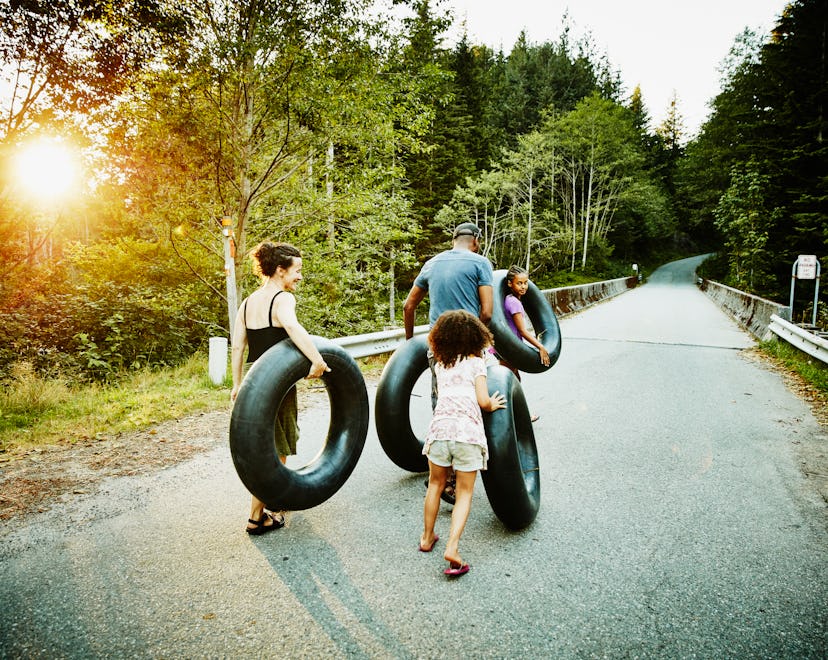 Family carrying inner tubes down empty road after swim on summer evening