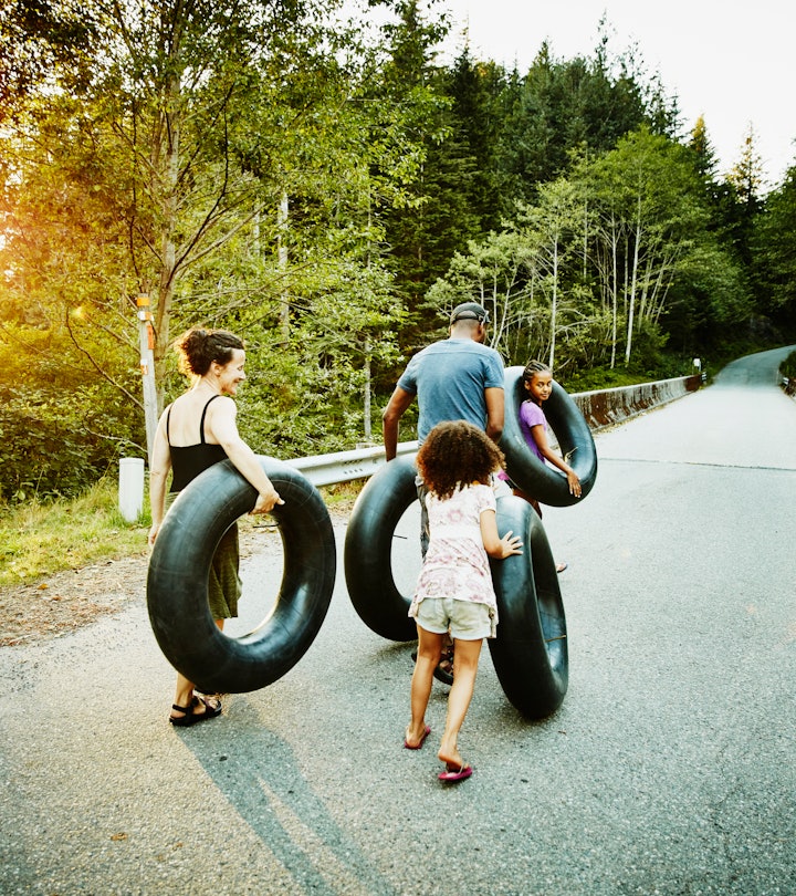 Family carrying inner tubes down empty road after swim on summer evening