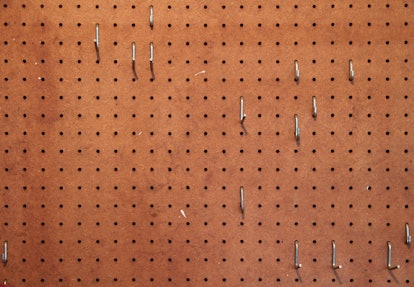 Empty pegboard with hooks for hanging tools in a woodworking shop .