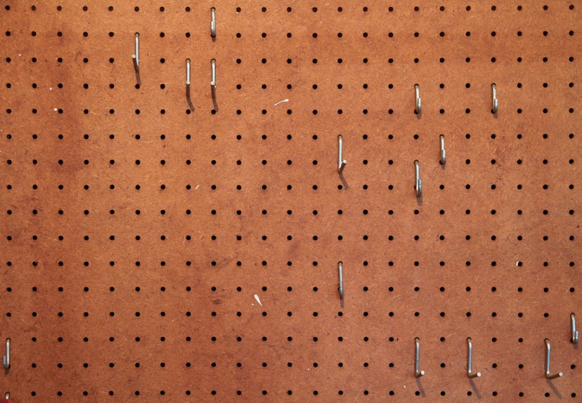 Empty pegboard with hooks for hanging tools in a woodworking shop .