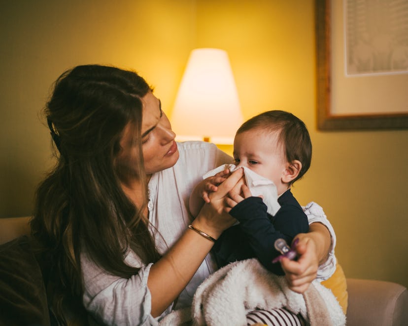 a mother wipes her baby's nose in an article about helping baby breathe better with a cold