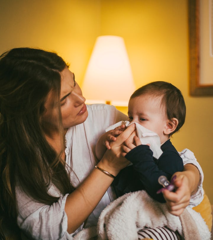 a mother wipes her baby's nose in an article about helping baby breathe better with a cold 