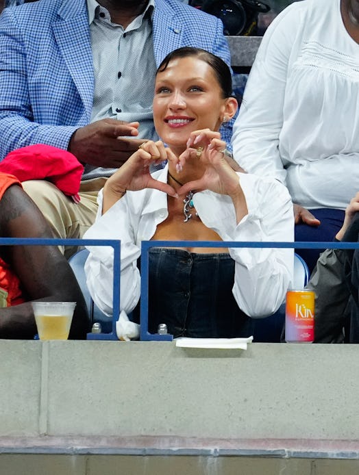 Bella Hadid sits courtside in a denim corset and white shirt at the 2022 us open
