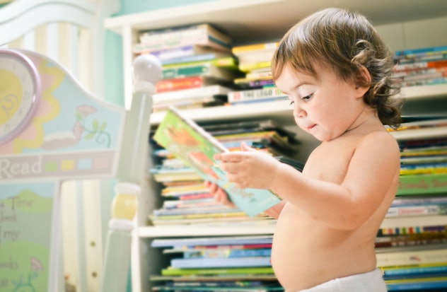 A baby girl sitting in a room with books. baby girl literary girl names