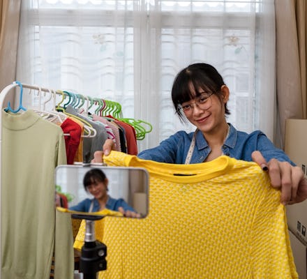 Young Asian woman selling online clothing using smart phone via social media at home, Internet or wi...