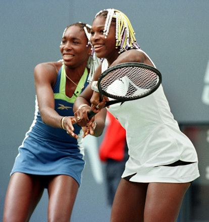 Sisters Venus (L) and Serena (R) Williams share a racket during an exhibition match 29 August at the...