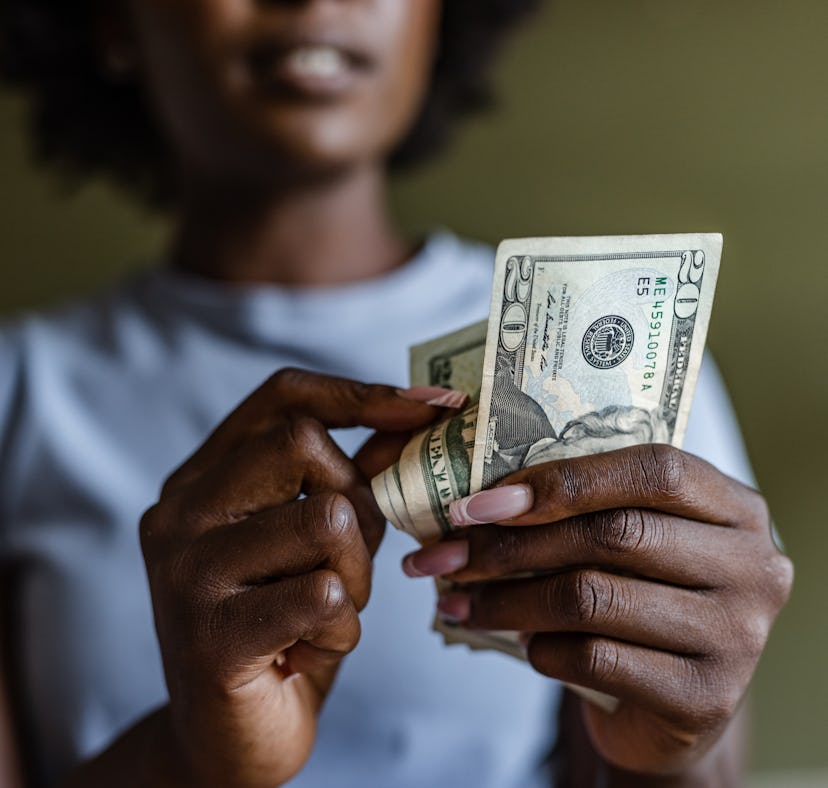 African American woman holding and counting dollars. Home budget planning.