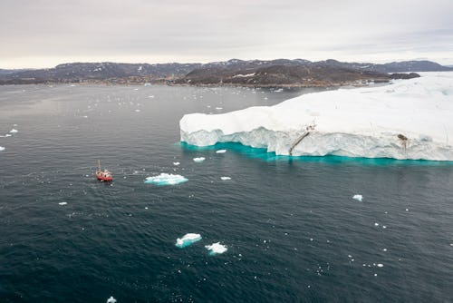 A typical Greenlandic fishing boat in front of the huge icebergs of the (Ilullisat) Icefjord, Disko...