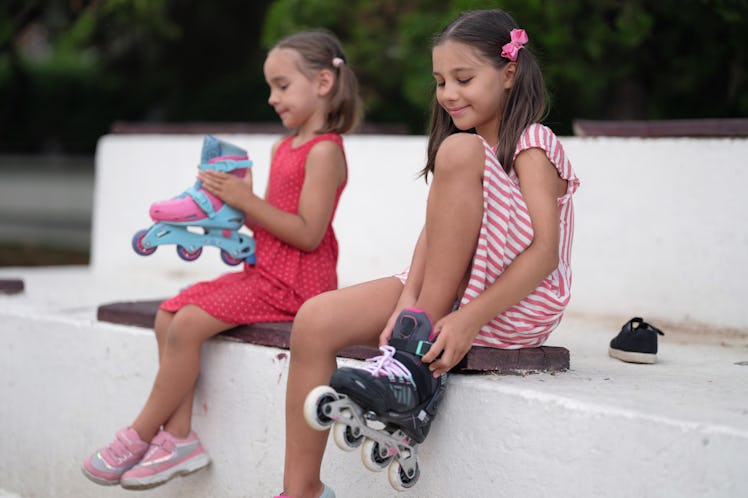 Portrait Of Happy Child Girls Preparing For Skating