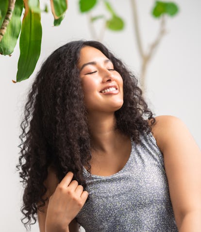 Young woman smiling to herself to symbolize the sixth house in astrology, aka the "house of health."