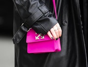 PARIS, FRANCE - MARCH 03: A guest wears a black shiny leather long coat, silver rings, a neon pink s...