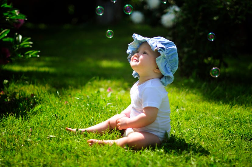 how hot is too hot for a baby? baby sitting on grassy lawn, looking at bubbles