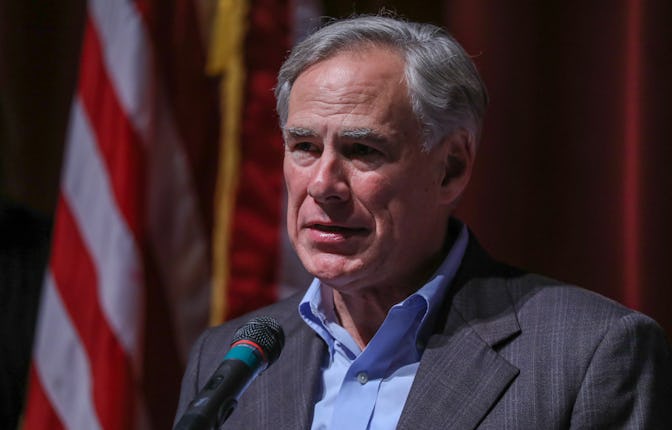 Texas Governor Greg Abbott standing in front of a microphone, with the American flag behind him.
