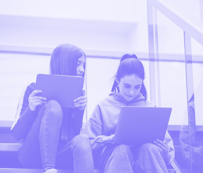 Girls on the high school stairs with laptop and tablet. Digital learning concept.