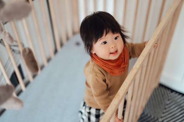 Happy baby girl standing in a crib in article about W names for girls