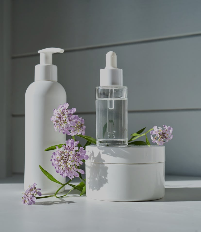 Skin care products on a chest of drawers against a white wooden wall.