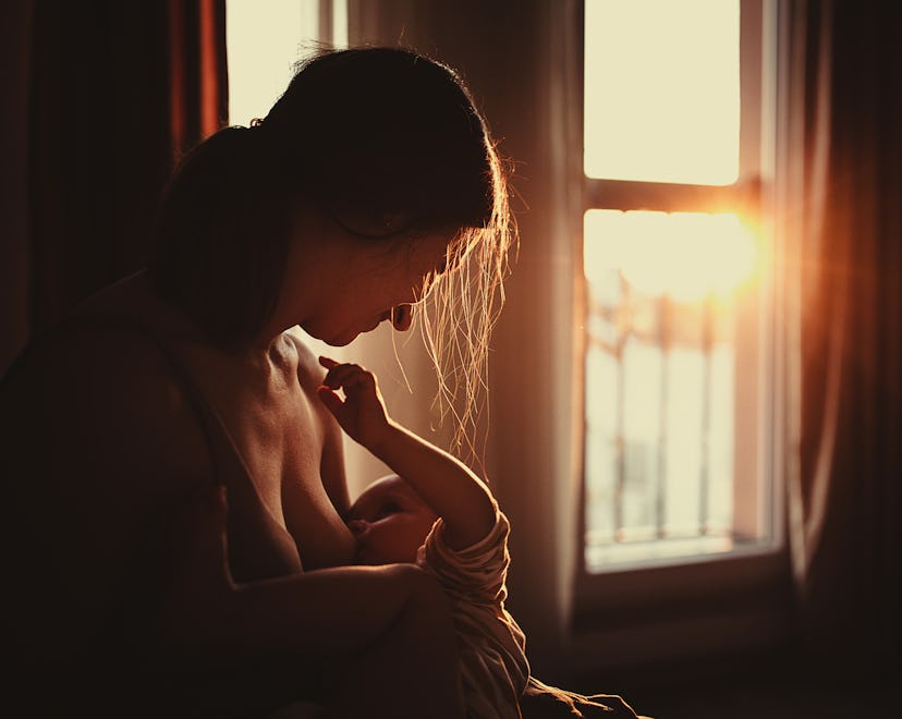 Mother breastfeeding her baby boy son in sunset at home in an article about how to tell if baby is e...