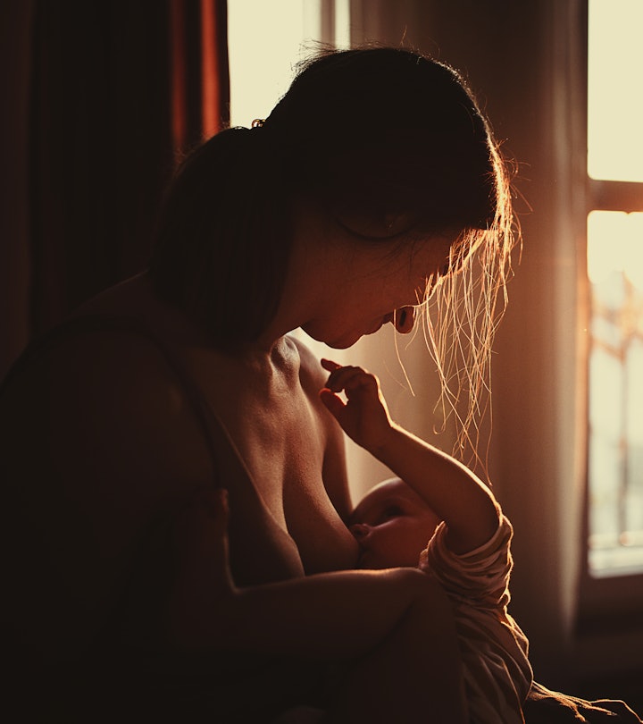 Mother breastfeeding her baby boy son in sunset at home in an article about how to tell if baby is e...
