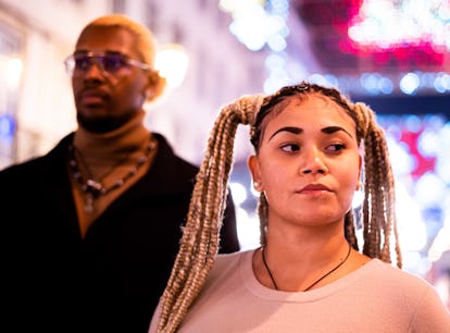 Focus on the serious face of a woman next to her african boyfriend outdoors at night