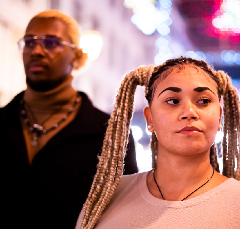 Focus on the serious face of a woman next to her african boyfriend outdoors at night