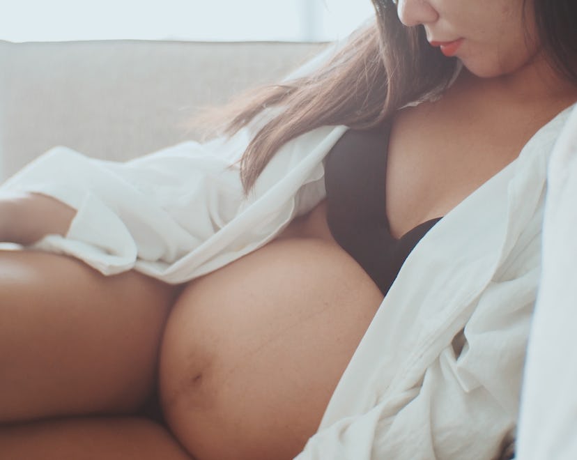 Pregnant woman with placenta previa sitting seductively in bra with an exposed stomach.