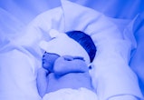 A premature infant being treated for bilirubin in an incubator. She is lying on her side wearing onl...