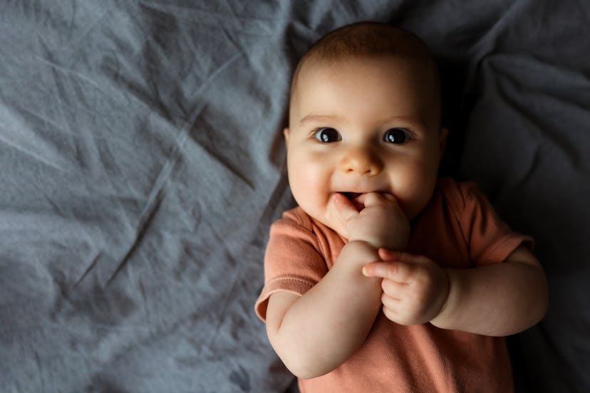 Happy baby smiling on a bed in an article about baby names that start with "W"