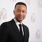 John Legend is on a red carpet in a suit