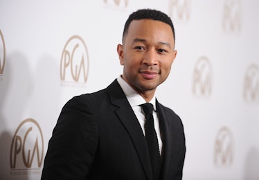 John Legend is on a red carpet in a suit