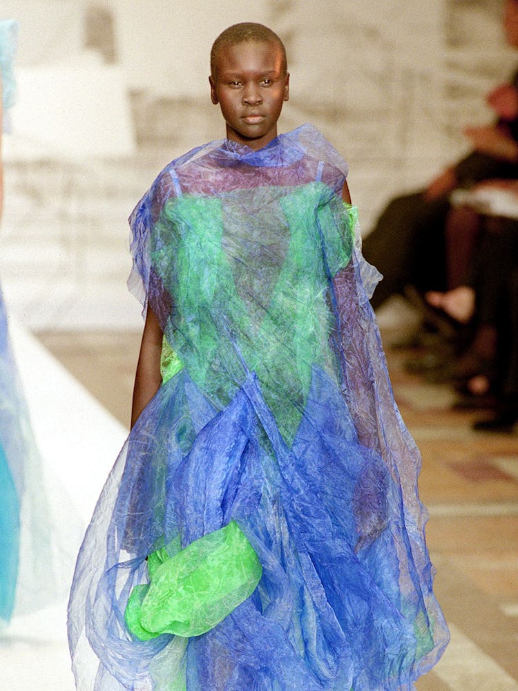A model in blue and green taffeta, layered, full dress by Issey Miyake for his Spring/Summer '99 rea...