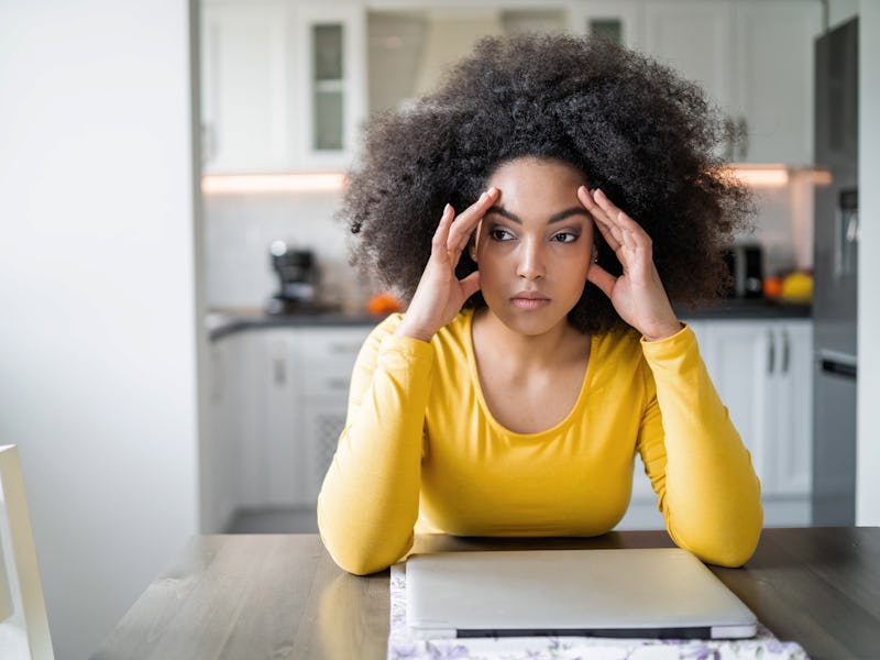 African american young woman dealing with financial problems and bills at home, sitting at the kitch...