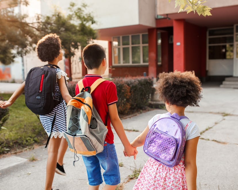 Three elementary school friends going to school, wearing new backpacks from back to school sales.