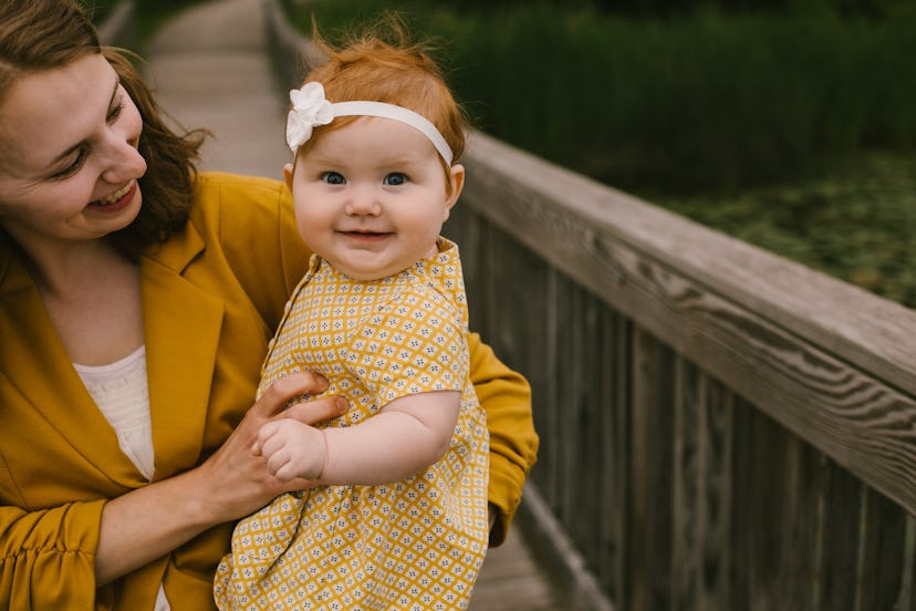 Baby held by mom smiling at the camera in article about Virgo names for baby girls