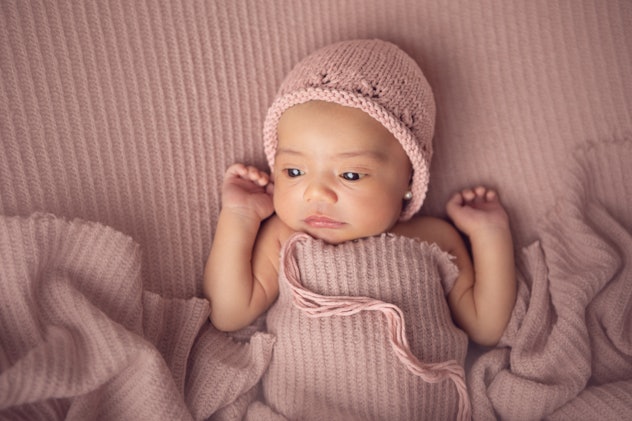 Cute newborn in pink knit in article about baby girl names for Virgo