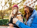 Two girls sitting in a park and drinking pumpkin spice latte