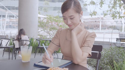 Young Asian woman working on a laptop or smartphone and taking notes at a out of office.