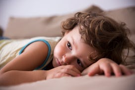 Child lit by diffused lighting, laying on the couch looking off into the distance.