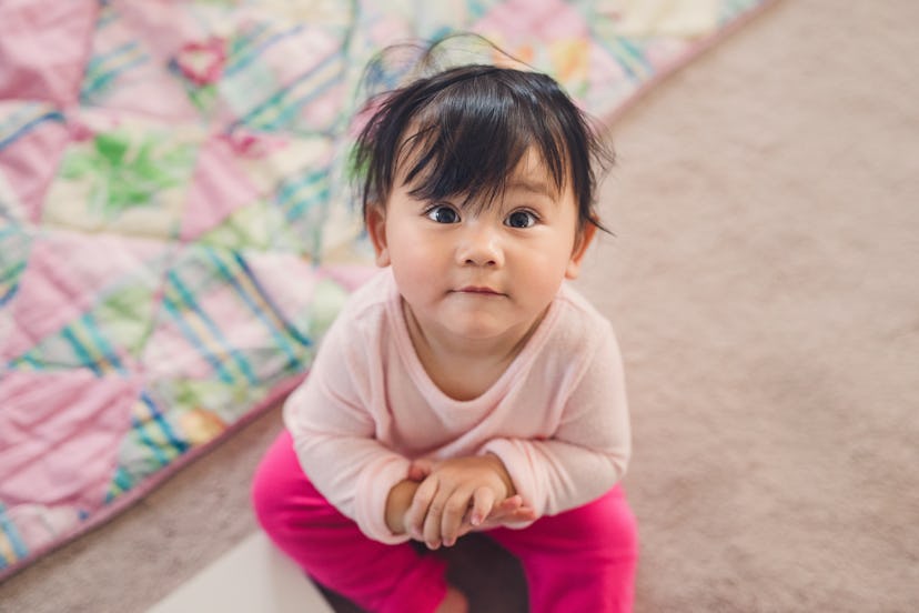 A cute 10 month old baby girl looks up at me with her big eyes to see if she can get what she wants ...