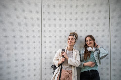 Portrait of female students walking around the university yard after class. Two female students afte...