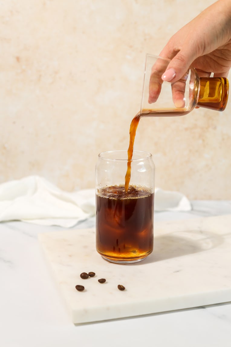 Hand pouring coffee cold brew carajillo espresso ice coffee with ice cubes