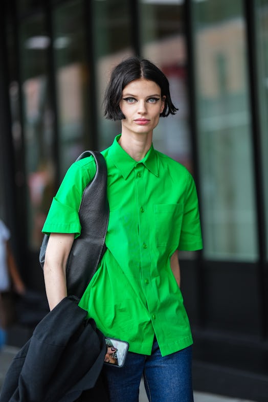 NEW YORK, NEW YORK - SEPTEMBER 11: A guest wears a neon green short sleeves shirt, a black matte lea...
