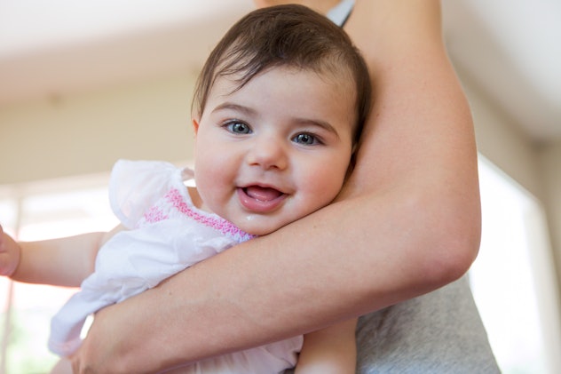 smiling happy baby in mother's arms in an article about girl names that start with "T"