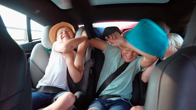 Two brothers play together in a car's back seat while their parents are in the roles of referees, tr...