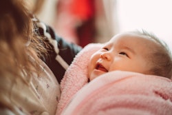 Adorable new born baby smiling joyfully at her mom in a round up of baby girl names that start with ...