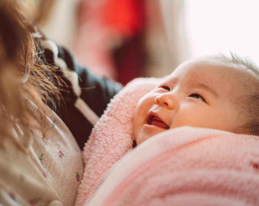 Adorable new born baby smiling joyfully at her mom in a round up of baby girl names that start with ...