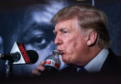 Former US President Donald Trump drinks a soda as he hosts the Holyfield vs Belford boxing match liv...