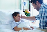 Loving father looking at ill son in bed at hospital ward